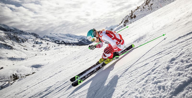 Ski -bestuurder in een rood en wit racepak in een extreme helling bij het vertrek