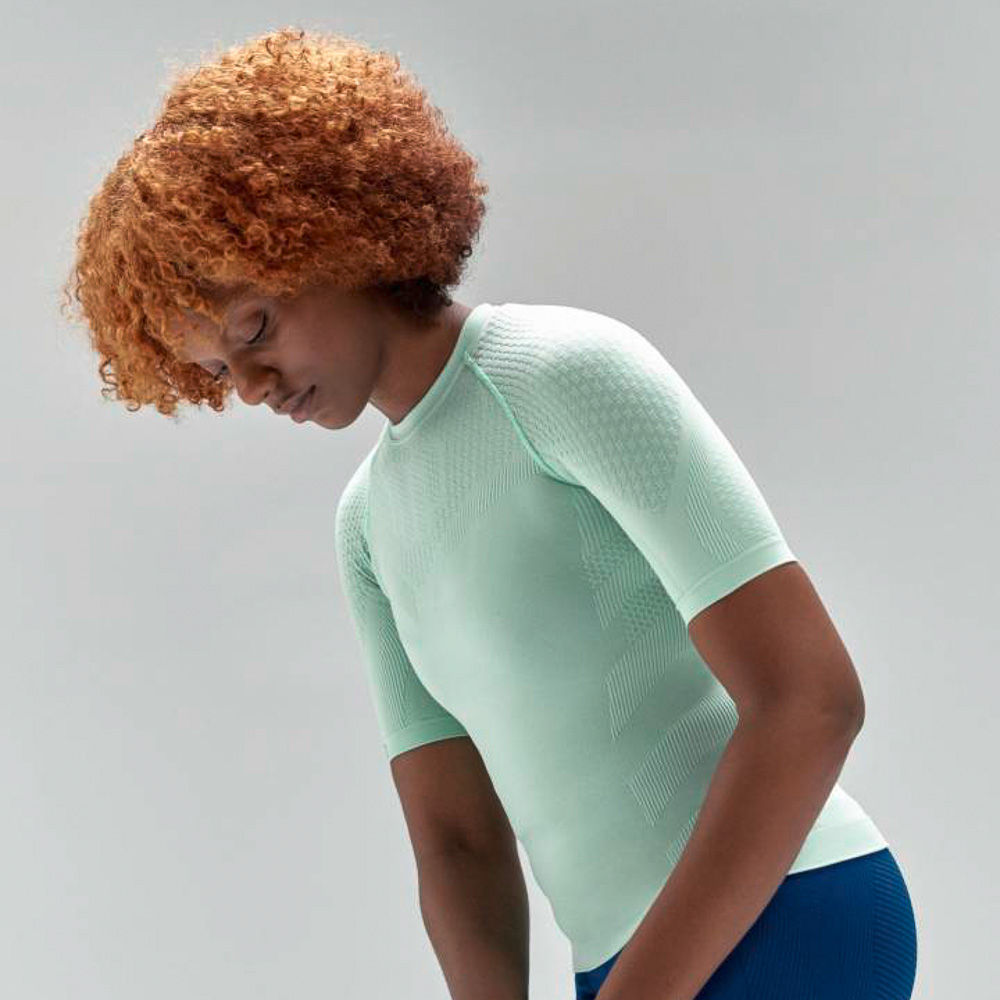 Mintgroene compressietop voor dames Vrouw met rode krullen en mintgroene sporttop rekt zich iets uit