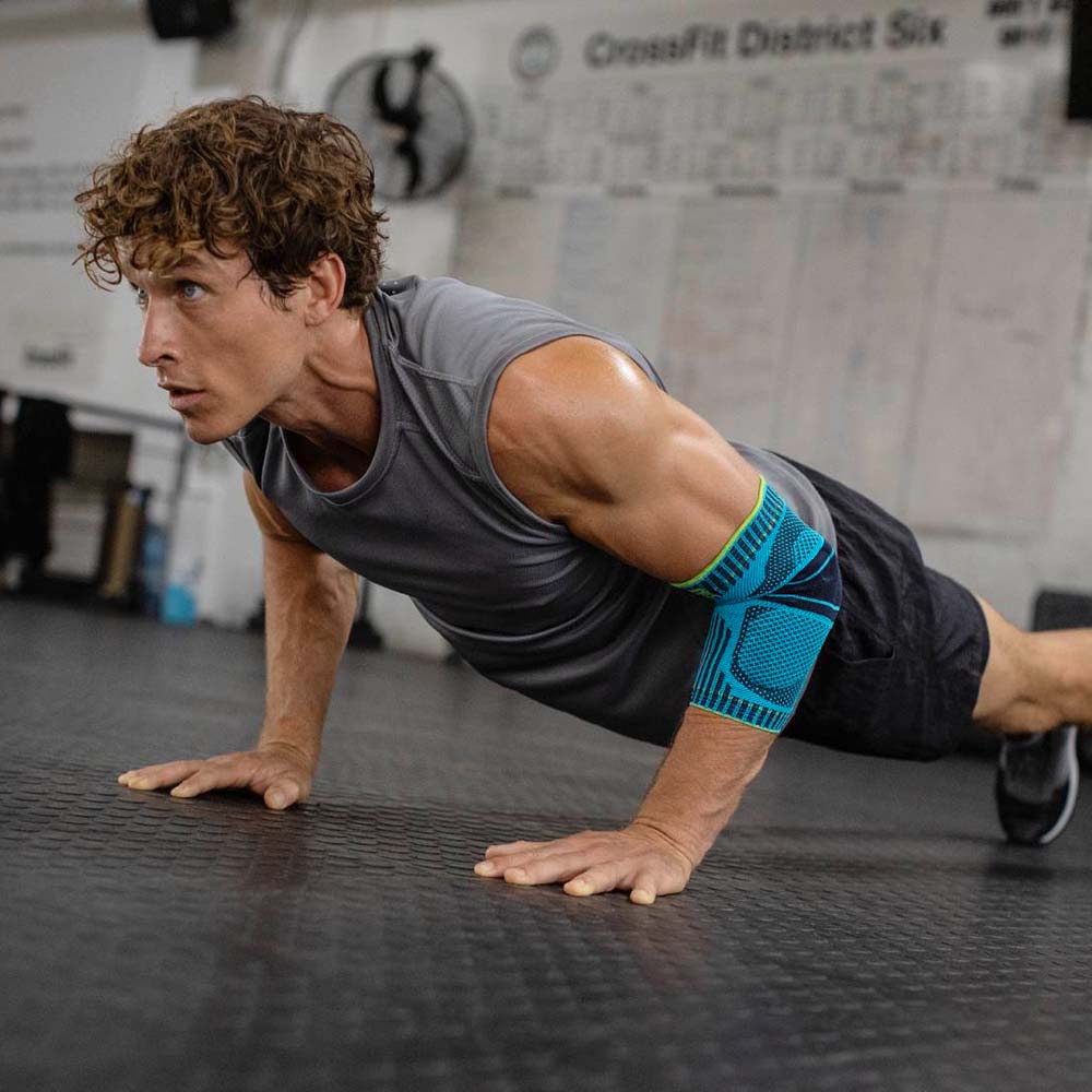 Ellenbogen verband bij fitness Jonge man doet push-ups in een sportschool en draagt een elleboogverband in Rivera